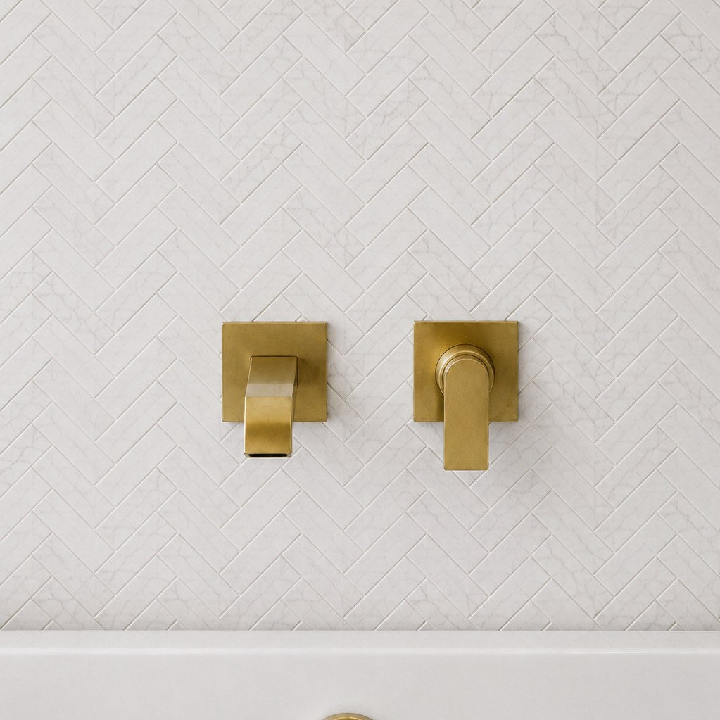 Carrara Petite Herringbone Mosaic Tile behind a bath with wall-mounted taps. Reference installation photographed by our supplier.
