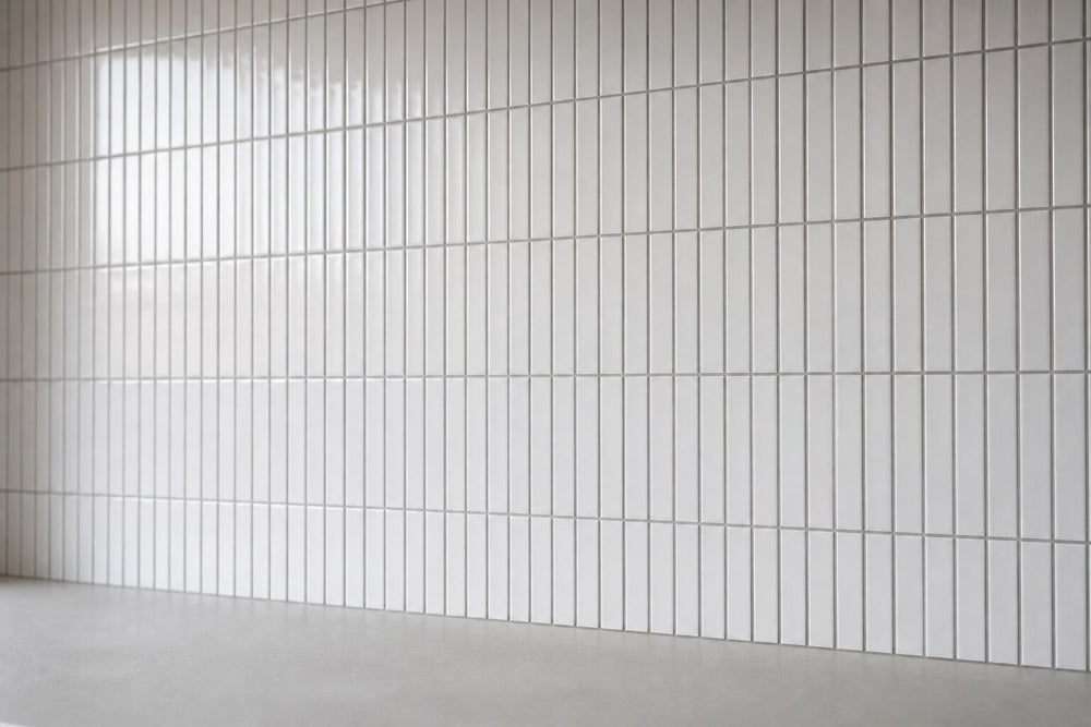 Editorial scene: slim white gloss finger mosaic tiles laid in a vertical stacked grid with grey grout above a plain bench, cool daylight. Generated illustration, not a Tilekind product.