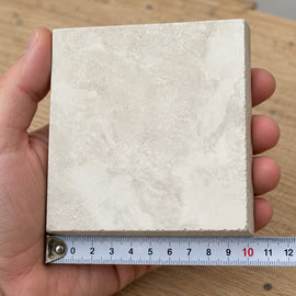 Atlas Ivory Stone-Look Tile sample held in a hand.