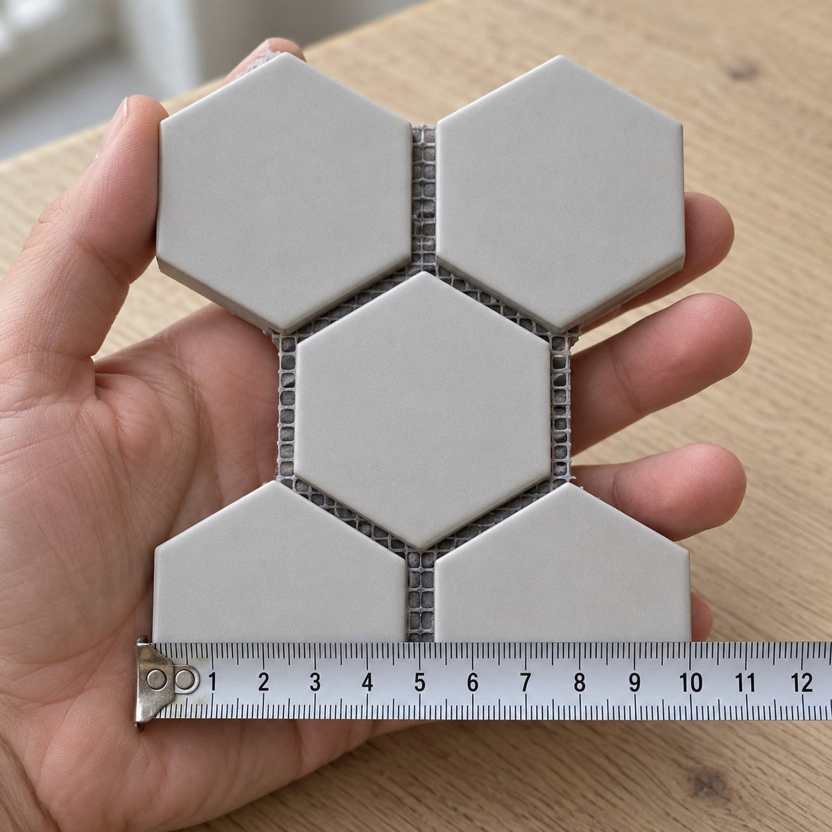 Carrara Hexagon Mosaic Tile sample held in a hand.