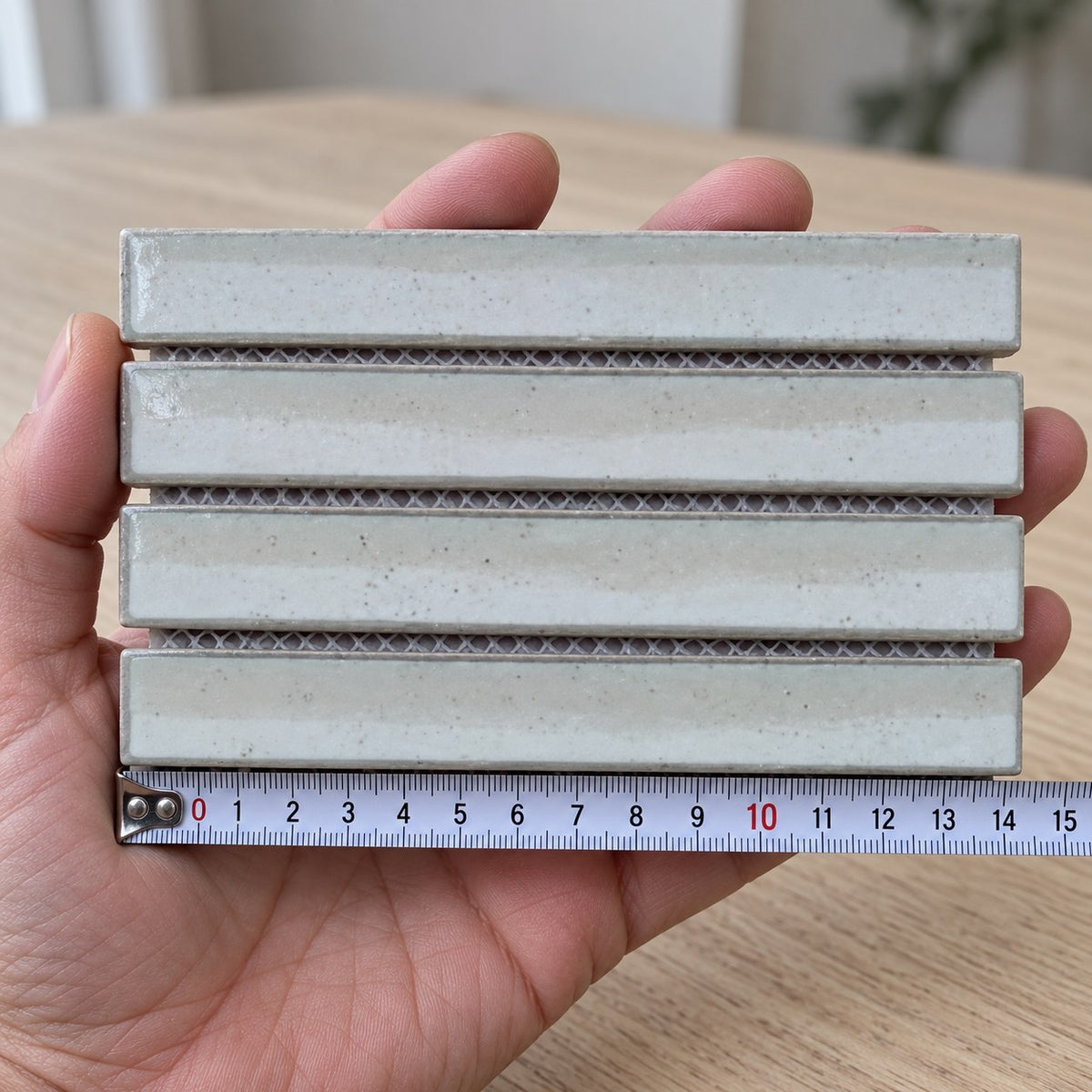 Carrara White Strip Mosaic Tile sample held in a hand.