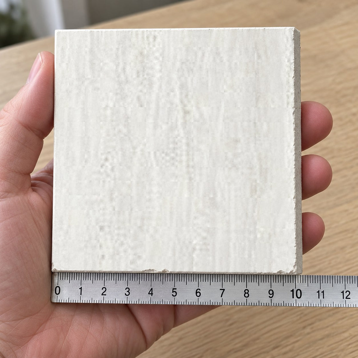 Coastal Alabaster Travertine-Look Tile sample held in a hand.