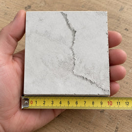 Coastal Dune Travertine-Look Tile sample held in a hand.