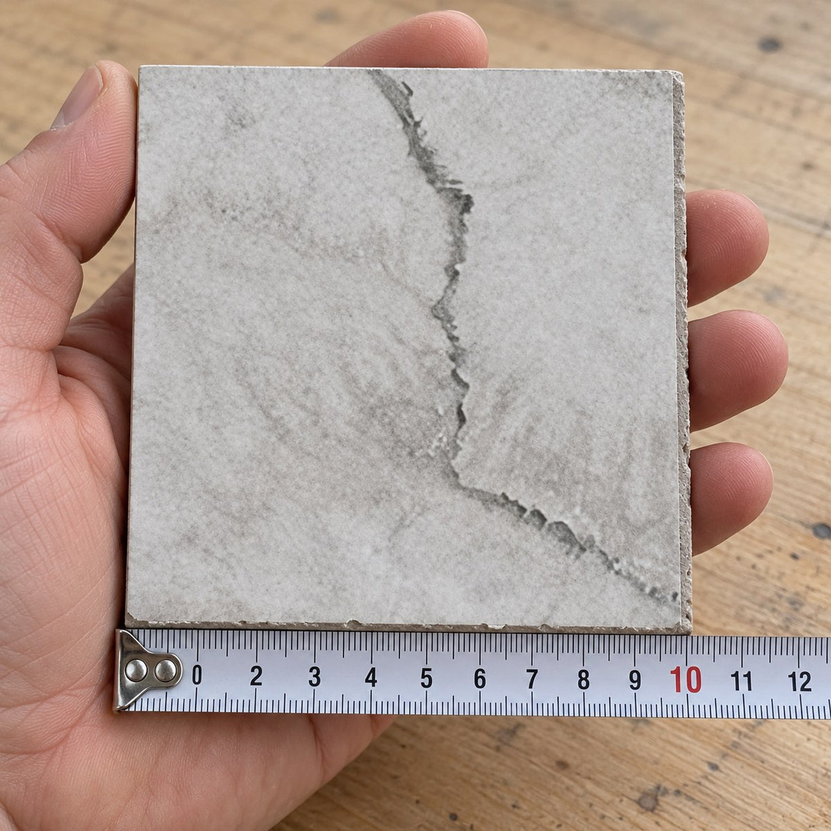 Coastal Mist Travertine-Look Tile sample held in a hand.