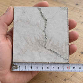 Coastal Mist Travertine-Look Tile sample held in a hand.