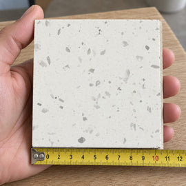Haven Fine White Terrazzo-Look Tile sample held in a hand.