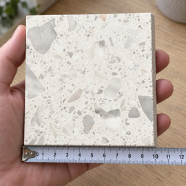 Haven White Terrazzo-Look Tile sample held in a hand.