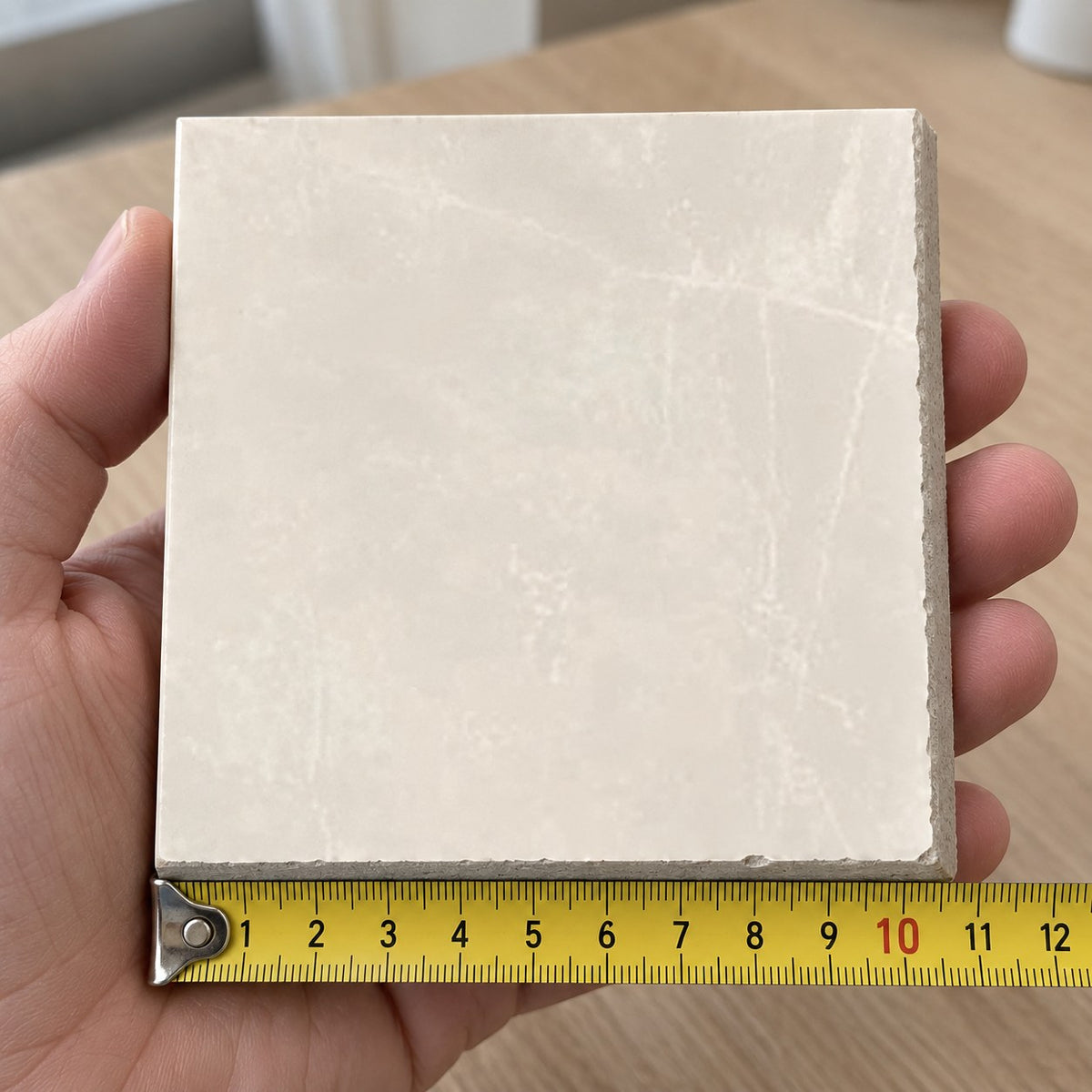 Pietra Cream Marble-Look Tile sample held in a hand.
