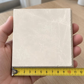 Pietra Cream Marble-Look Tile sample held in a hand.