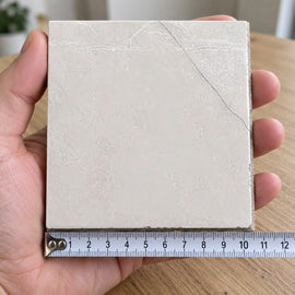 Pietra Latte Marble-Look Tile sample held in a hand.