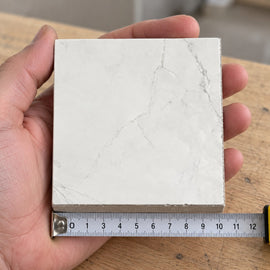 Pietra Perla Marble-Look Tile sample held in a hand.