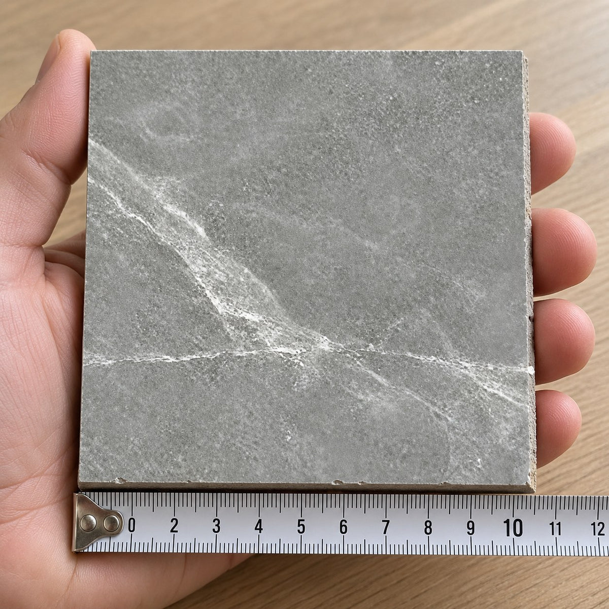 Pietra Shadow Marble-Look Tile sample held in a hand.