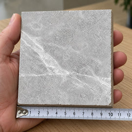 Pietra Smoke Marble-Look Tile sample held in a hand.
