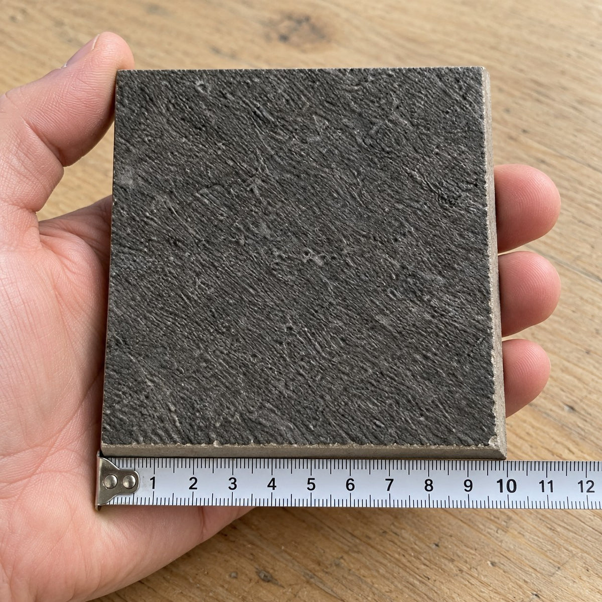 Ridge Charcoal Stone-Look Tile sample held in a hand.