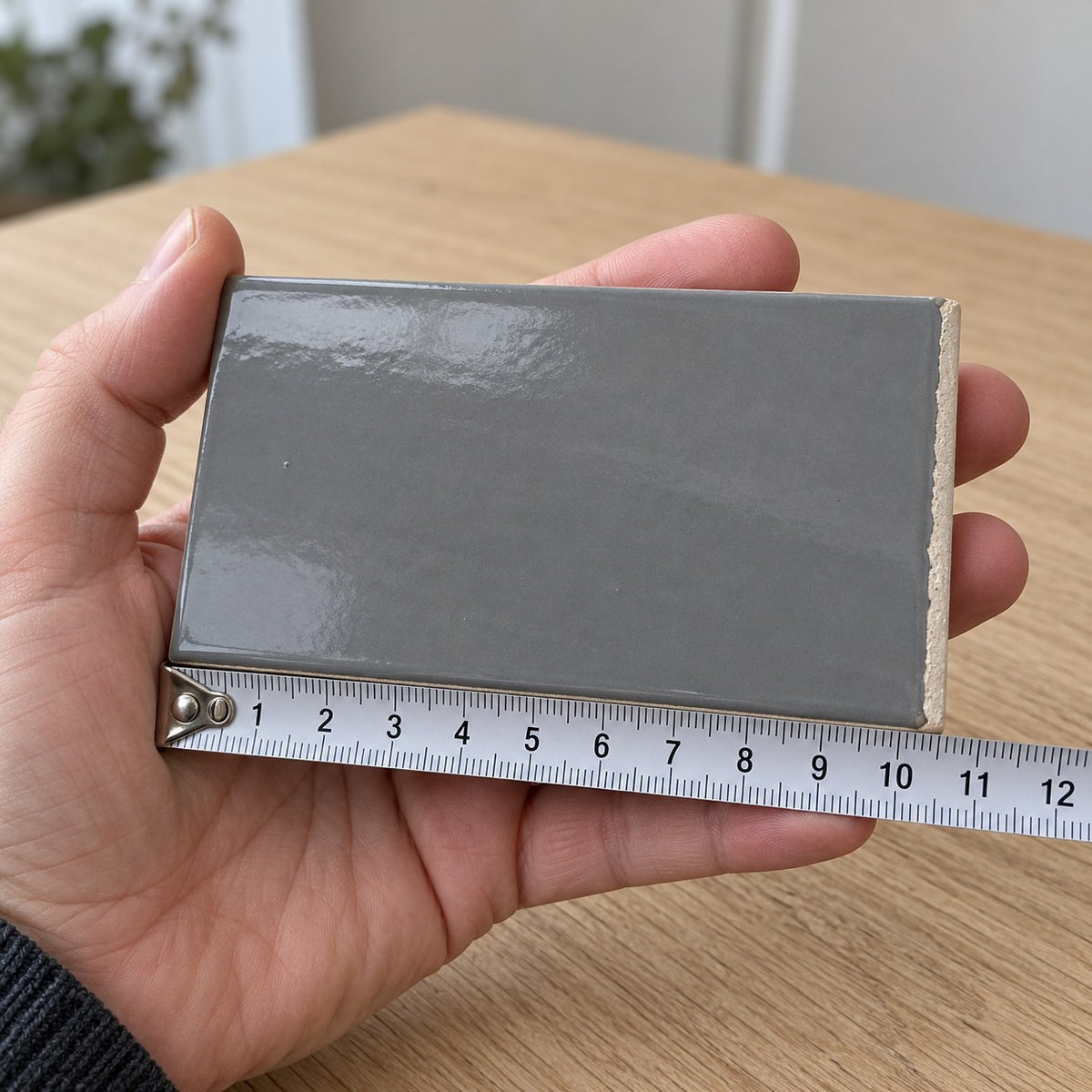 Studio Charcoal Subway Tile sample held in a hand.