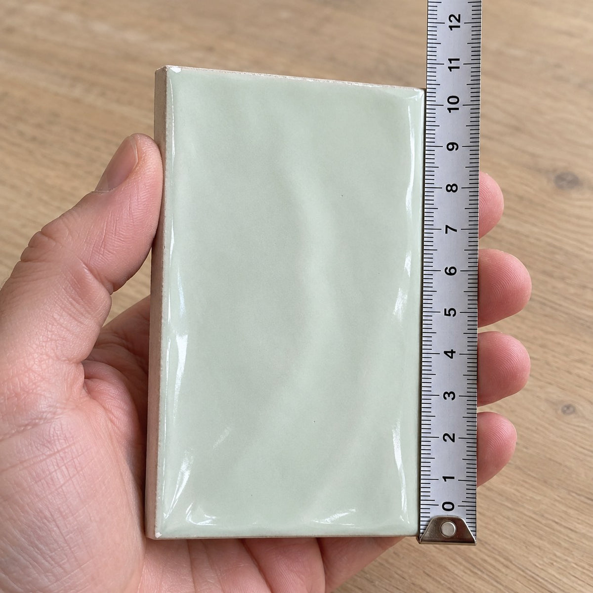 Studio Sage Wave Subway Tile sample held in a hand.