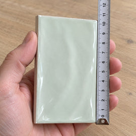 Studio Sage Wave Subway Tile sample held in a hand.