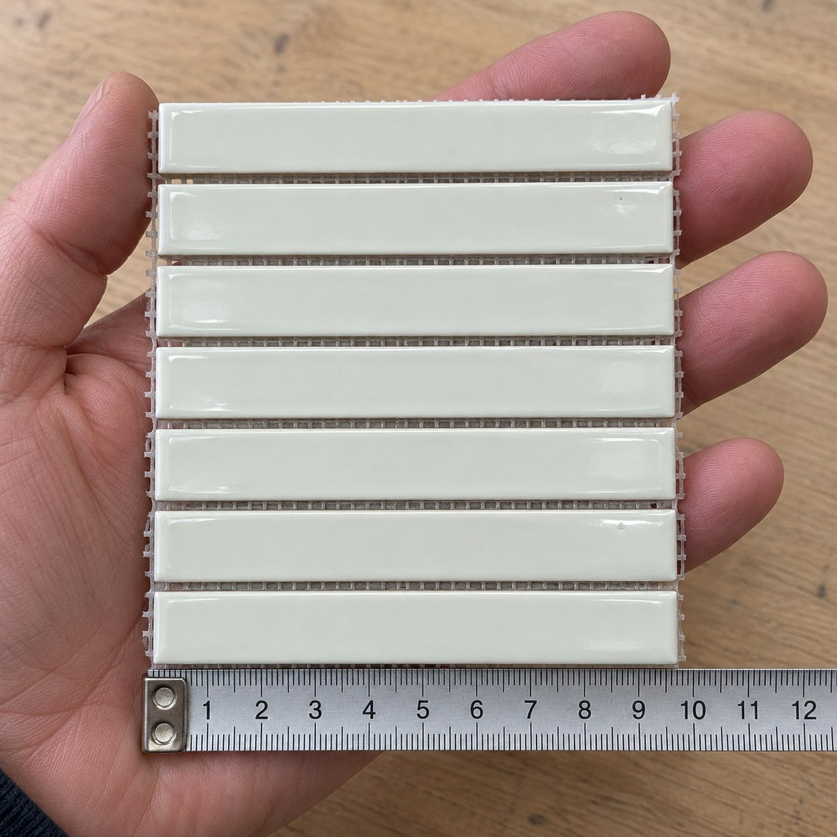 Studio White Finger Mosaic Tile sample held in a hand.