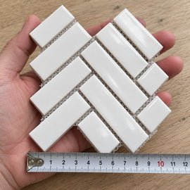 Studio White Herringbone Mosaic Tile sample held in a hand.